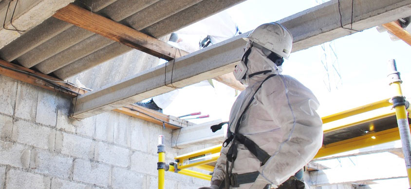 asbestos surveyor in a protective suit looking at a roof
